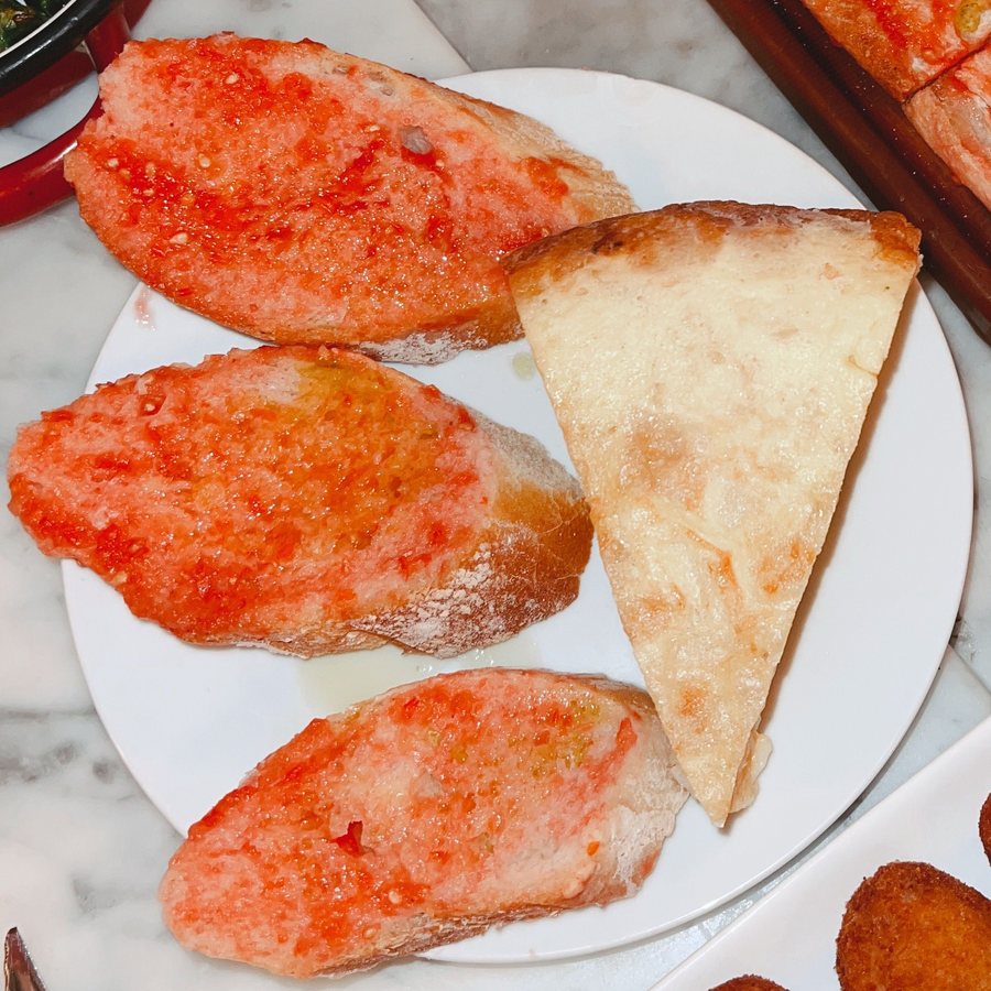 Pan con tomate y anchoas en plato blanco